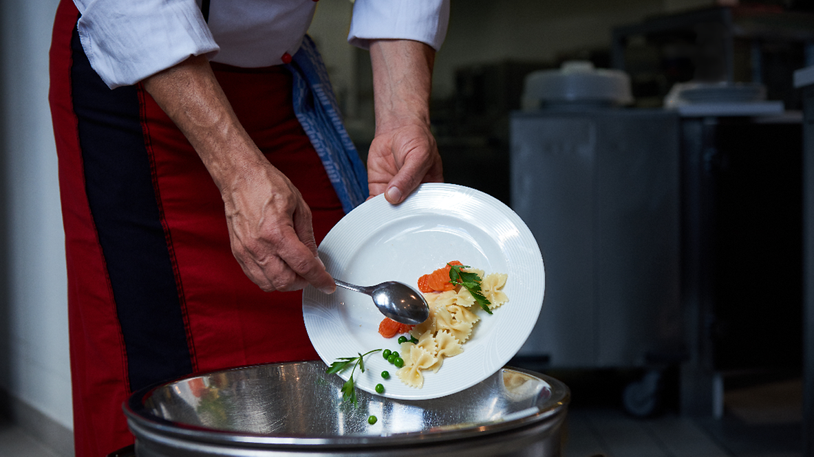 Food scraps are thrown from a plate into waste garbage can.