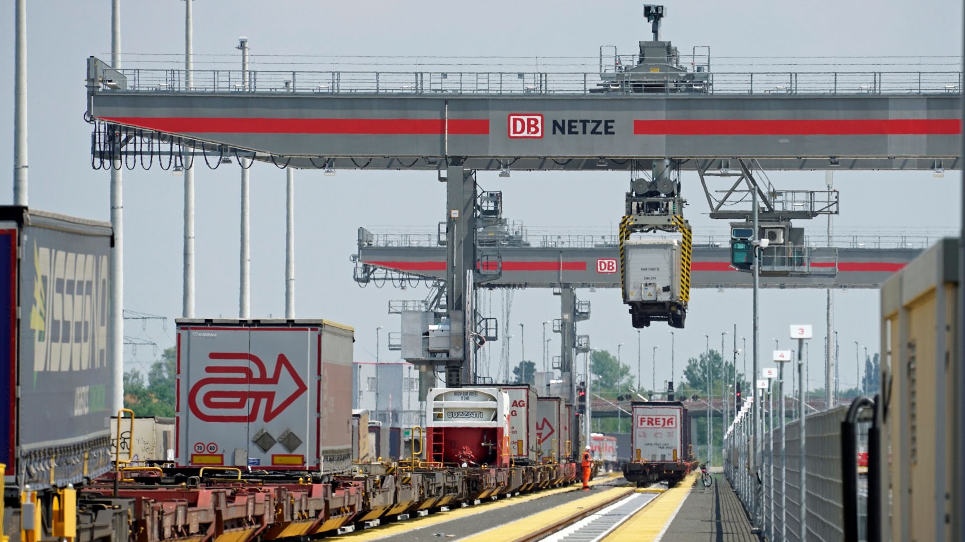 A freight train that is unloaded by cranes.