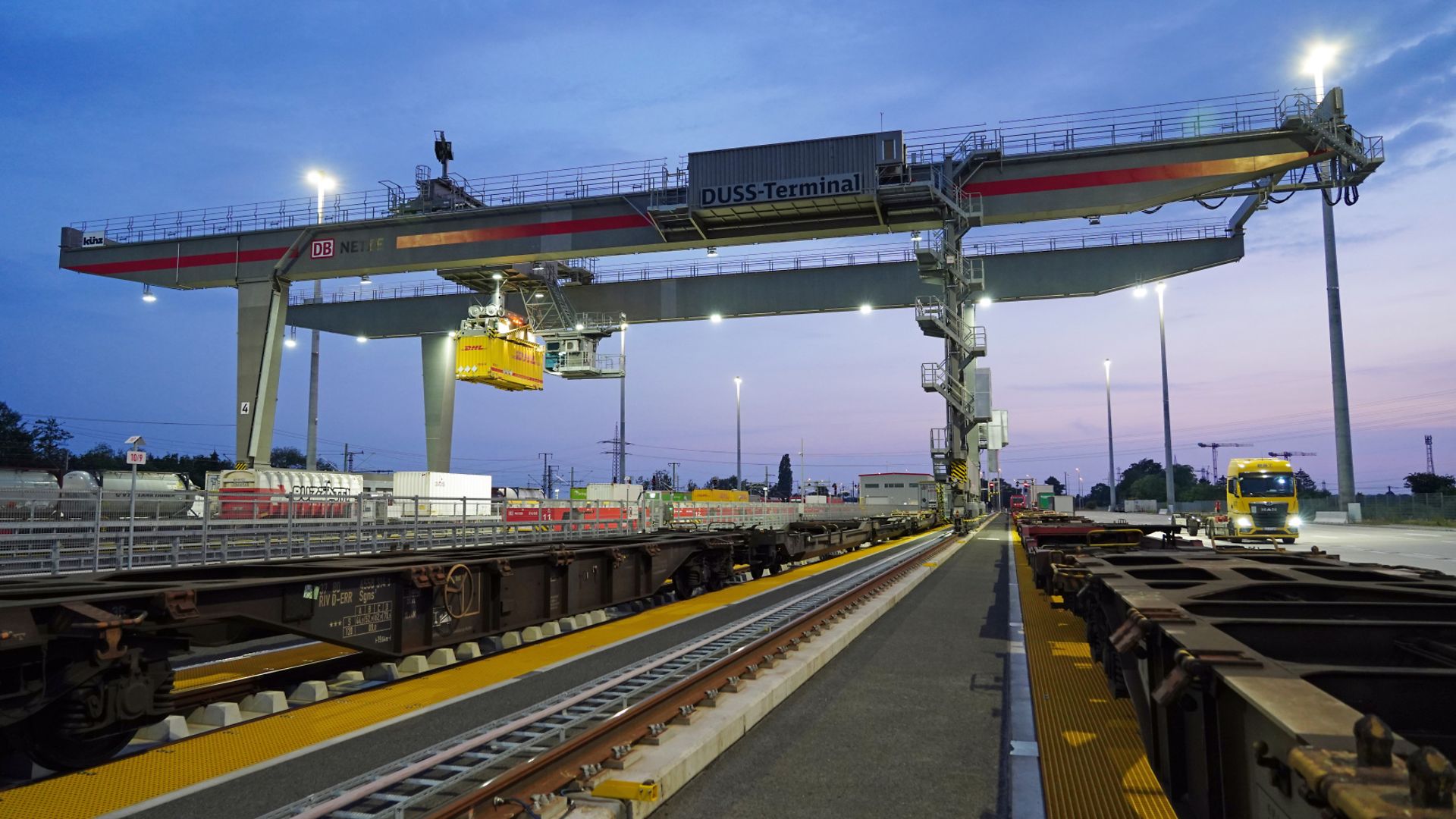 A crane unloading a train in the evening