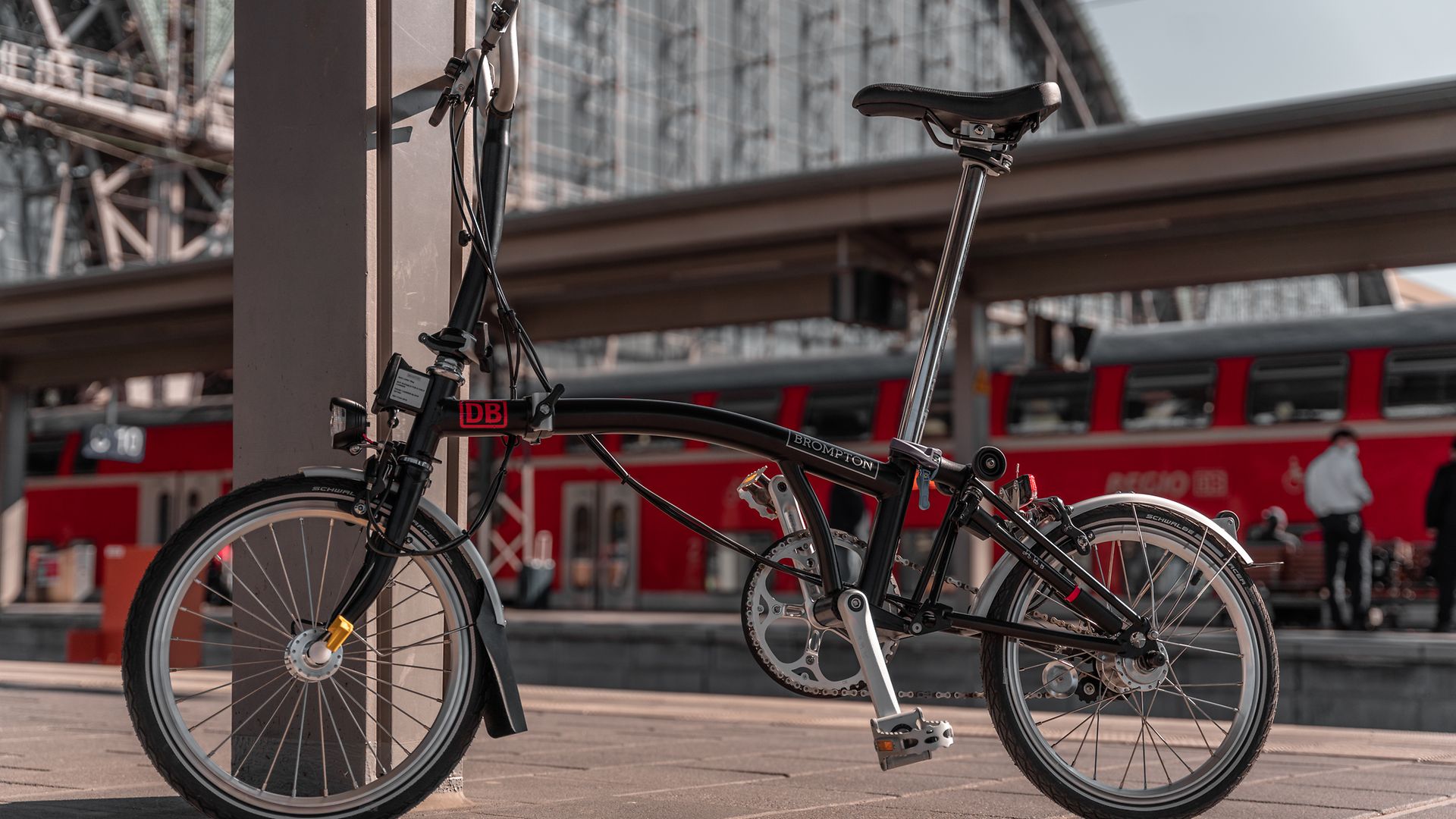 A folded folding bike on a track at the train station