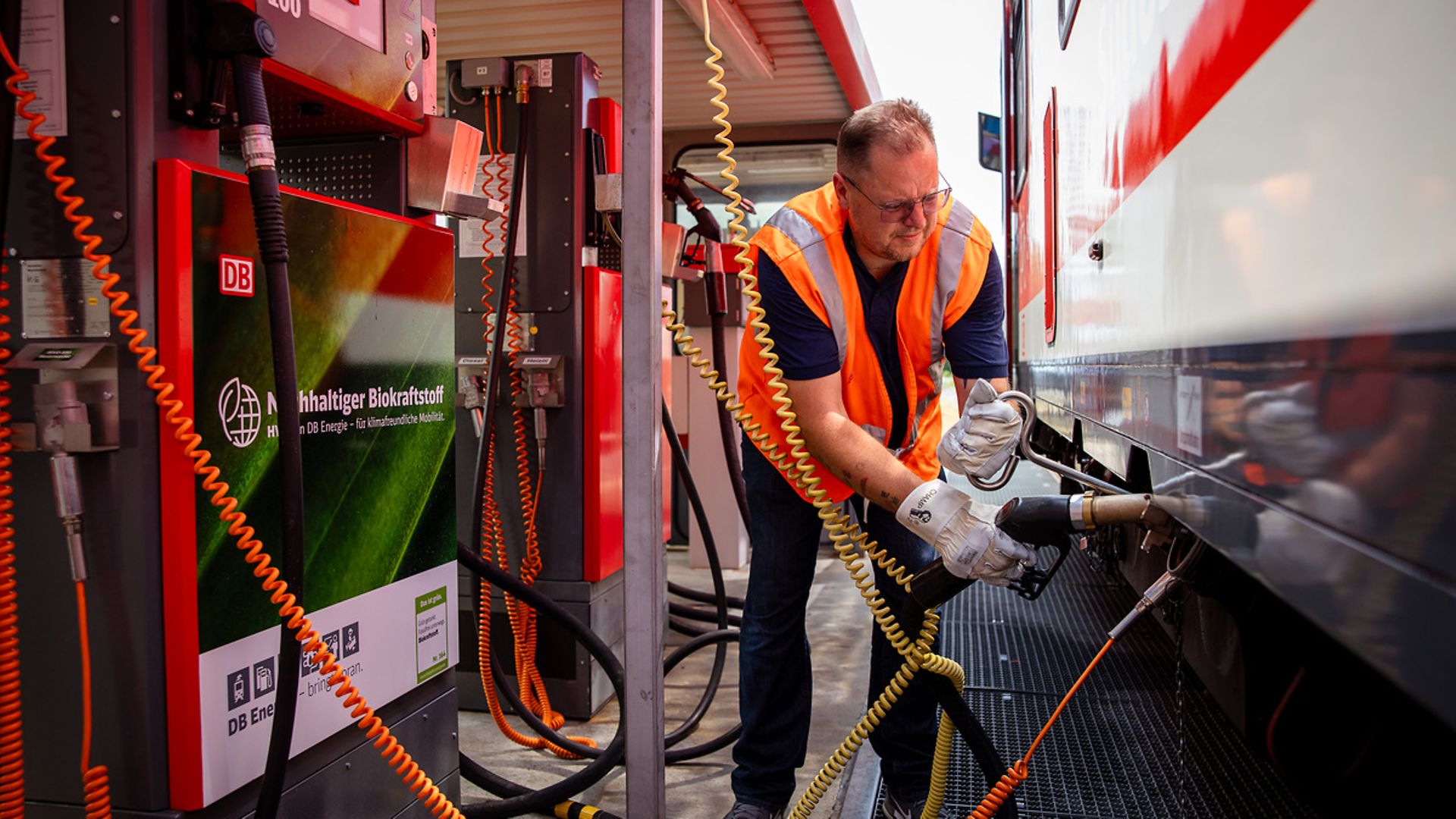 An employee refuels a train.
