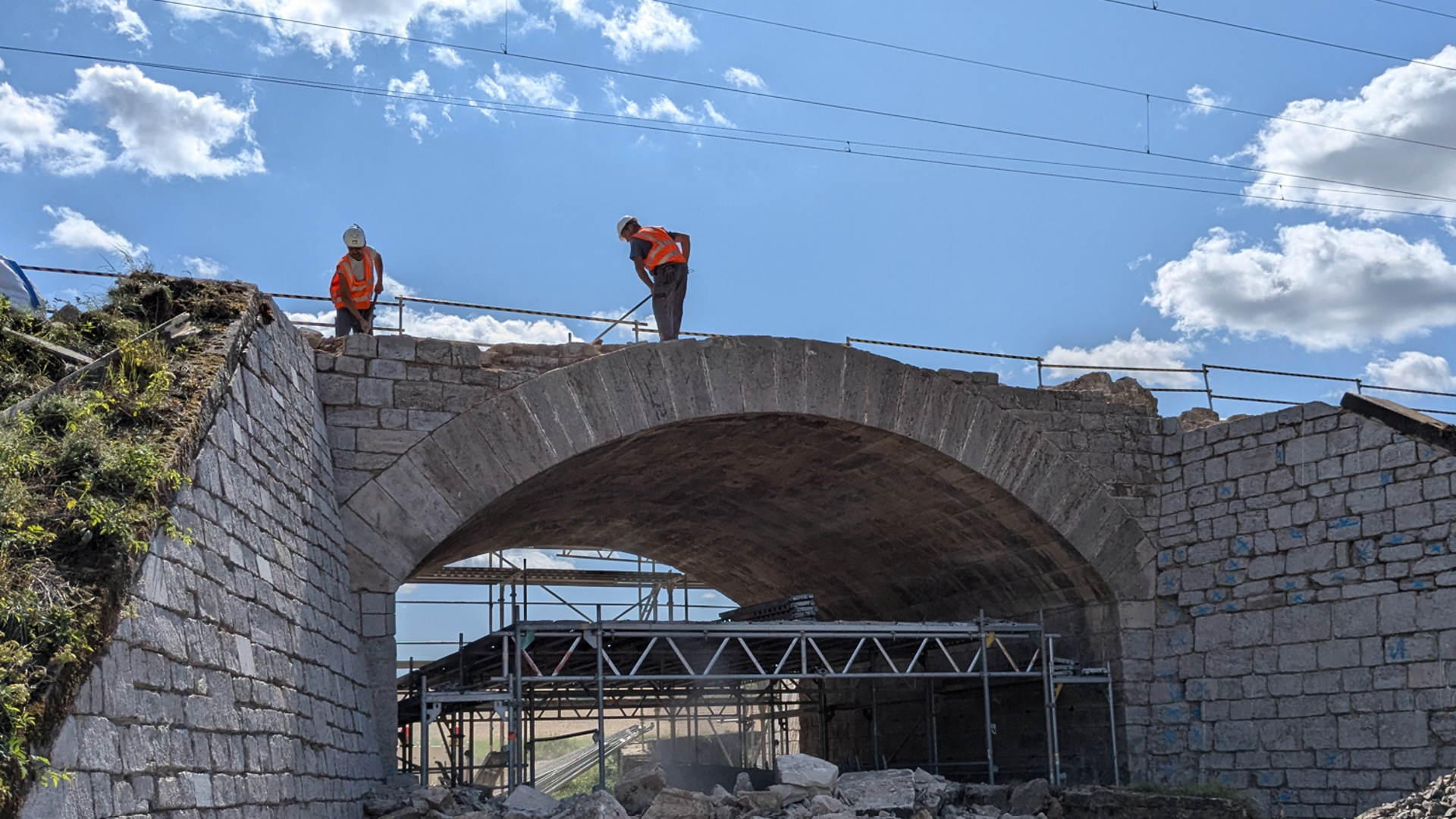Two construction workers on a small concrete bridge