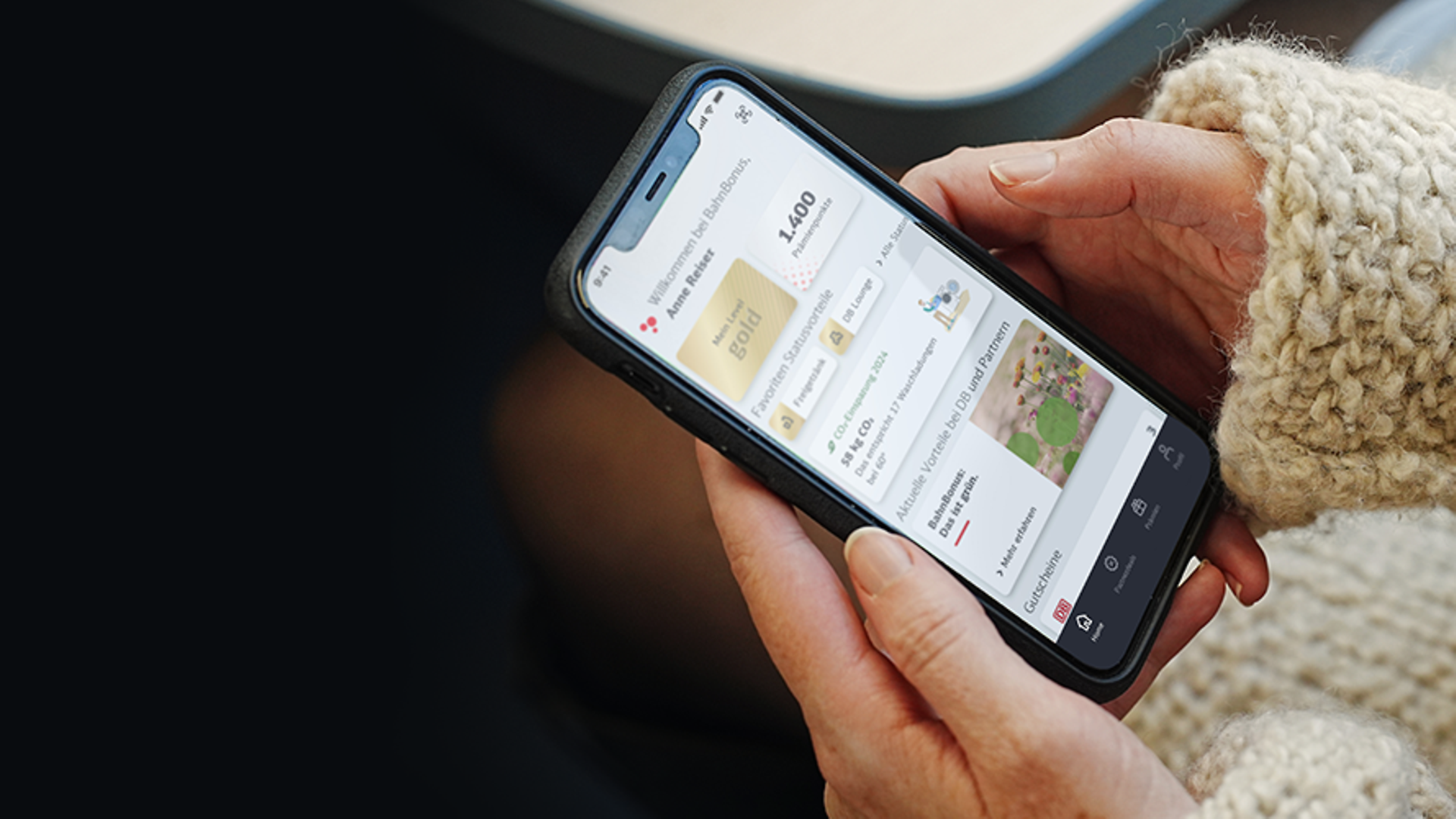 A woman is holding a cell phone with the BahnBonus loyalty program open.