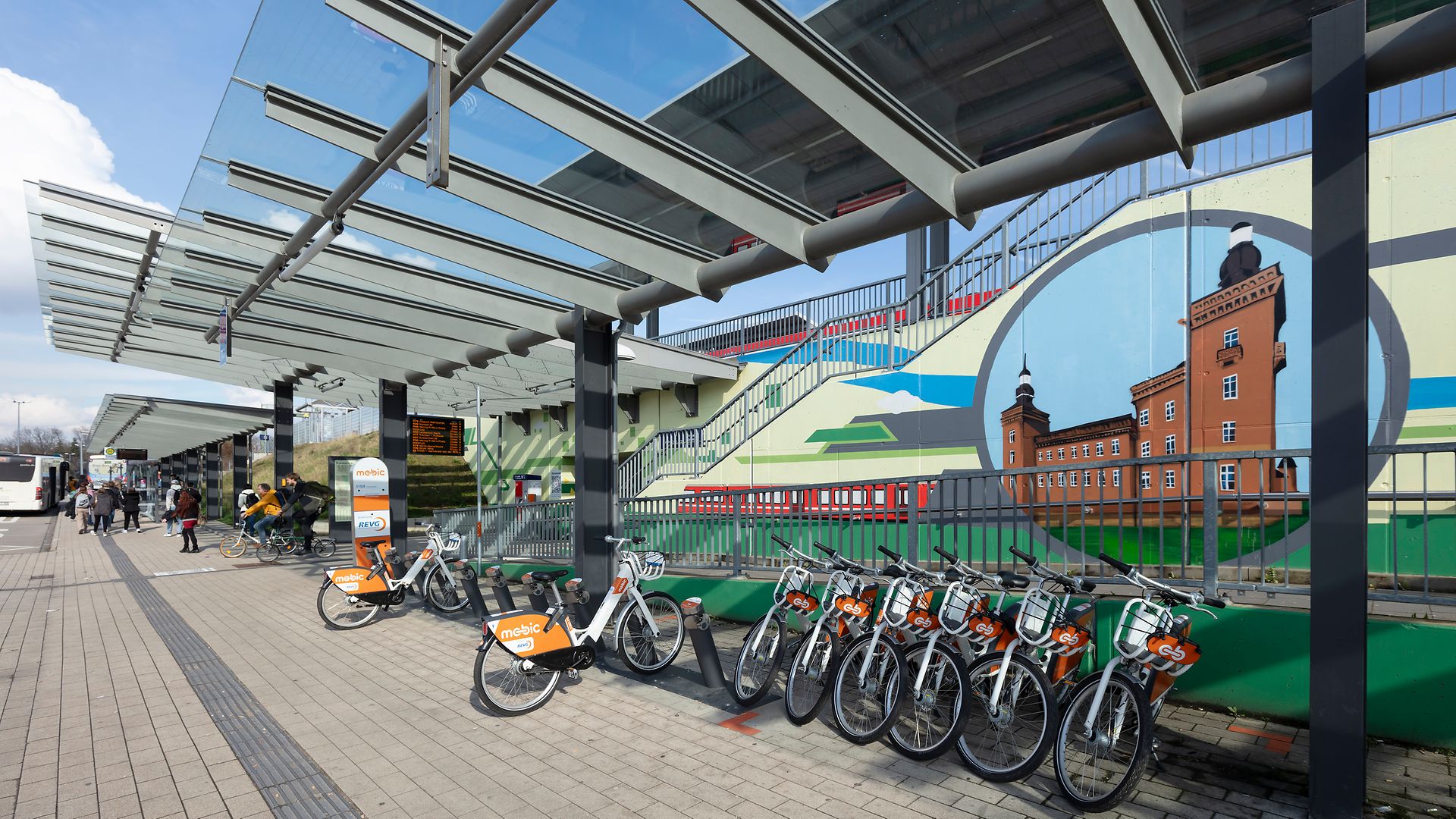 Rental bikes in front of a wall with a colorful landscape motif