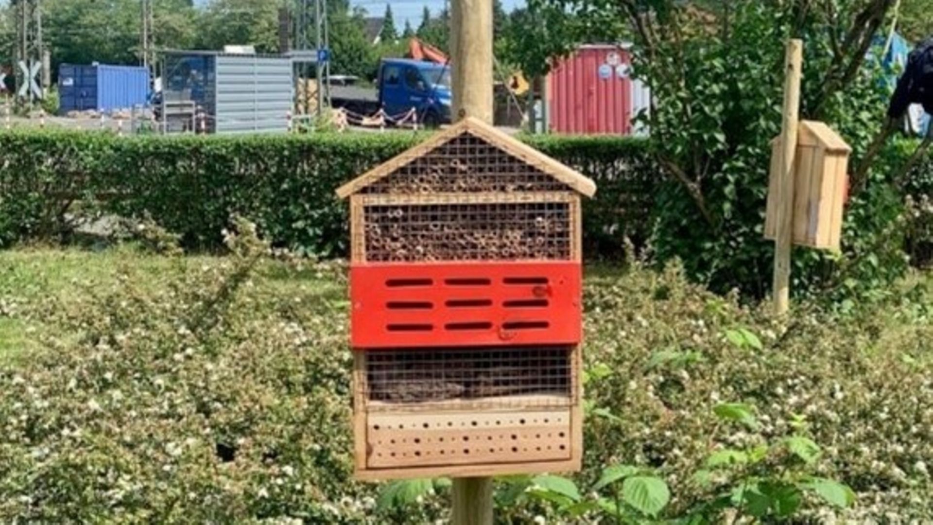 An insect hotel on a pole, parts of the plant in Düsseldorf can be seen in the background