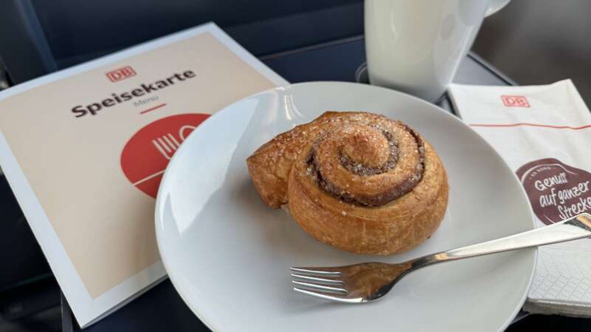 Unfolded table on the train with a plate of cinnamon buns and a napkin and menu from the on-board bistro