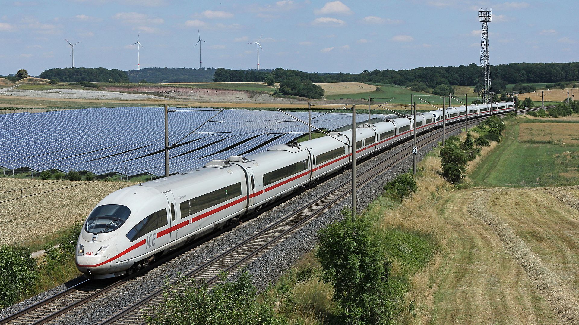 Zwei ICE 3 (Baureihe 403) fahren an einem Solarpark bei Hellmitzheim vorbei