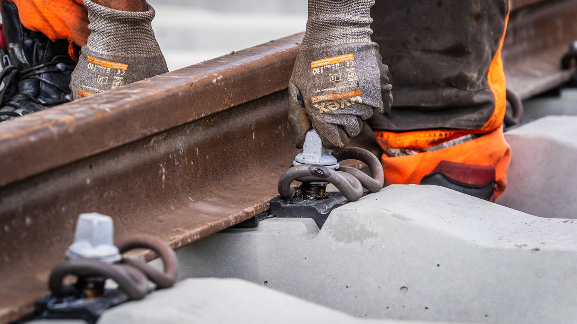 Ein Gleisbauarbeiter installiert Schrauben an einem Schienenstück.