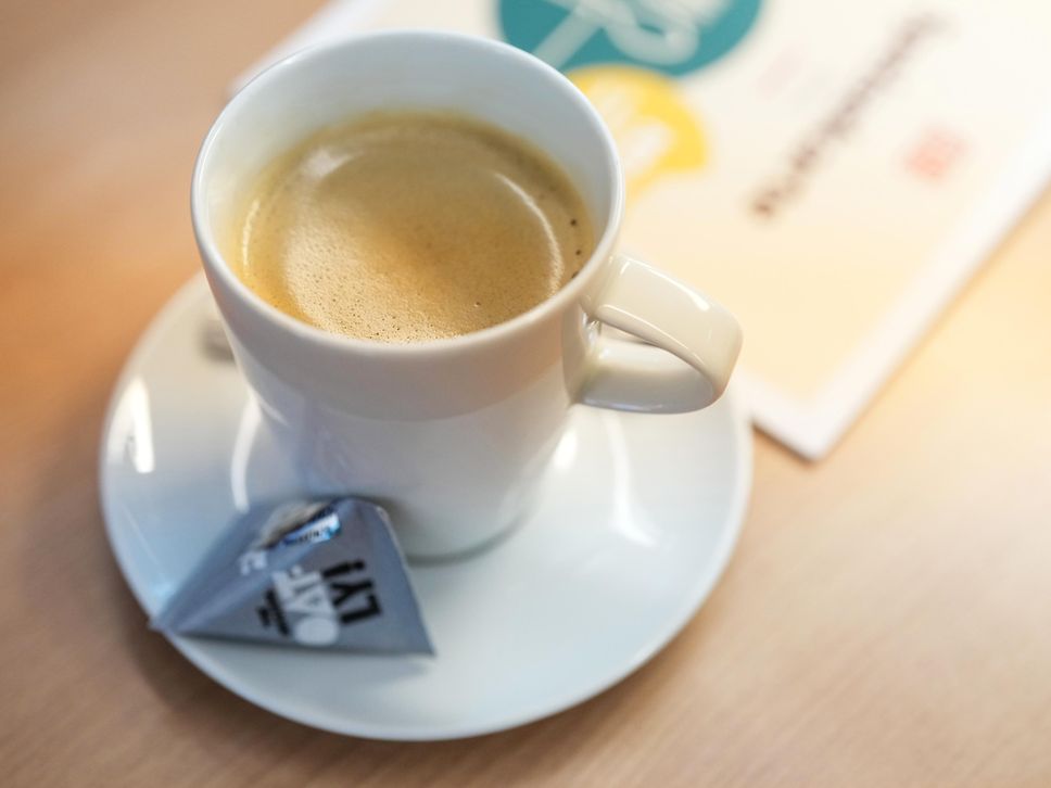 Eine Tasse mit Kaffee und daneben ein Päckchen Hafermilch der Firma Oatly